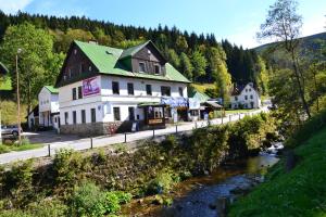a building with a green roof next to a river at Hostel Fortuna in Špindlerův Mlýn