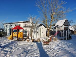 a snow covered yard with a playground and a building at Chalet im Spiel- und Obstgarten in Keidelheim