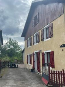 ein Gebäude mit roten Türen und einem Picknicktisch daneben in der Unterkunft Maison vosgienne 2 à 8 personnes in Rochesson