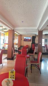 ein Restaurant mit roten Stühlen und Tischen sowie einem Flachbild-TV in der Unterkunft Deka B&B Ksh1500 in Nairobi