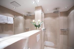 a bathroom with a shower and a vase of flowers at Haus Lesch - Stilvolle Appartements mit tollem Bergblick in Kreuth am Tegernsee in Kreuth