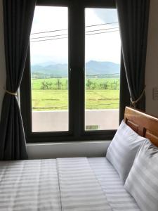 - une chambre avec un lit et une grande fenêtre dans l'établissement Happy field homestay, à Phong Nha