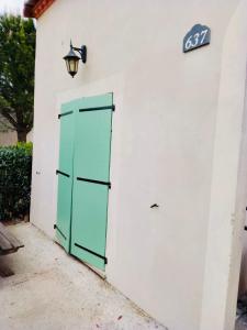 a green door on the side of a white building at La villa De Lina 637 -Self Check In - in Gallargues-Le-Montueux