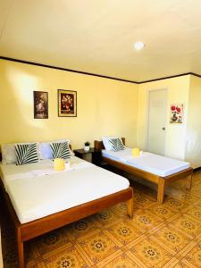 two beds are in a room with yellow walls at Edem Tourist Inn Malapascua in Malapascua Island
