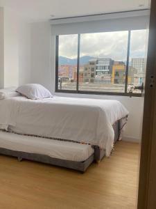 een bed in een kamer met een groot raam bij HOMY APARTAMENTOS - Corferias, embassy, airport, G12, UN, Agora in Bogota