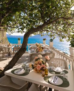 a table with plates and flowers on it on the beach at Hotel Liro - Adults Only in Vlorë