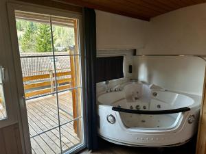 a bath tub in a room with a large window at Chalet Hotel Adler AG in Kandersteg