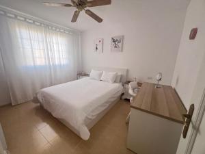 1 dormitorio con cama blanca y ventilador de techo en Laderas del Palmar Luxury, en Palm-mar