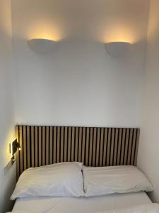 uma cama com duas almofadas brancas e duas luzes por cima em Exhibition Court Hotel 4 em Londres