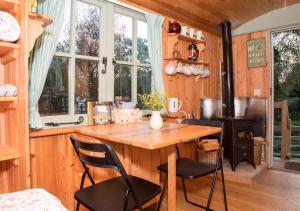 a kitchen with a wooden table and chairs and a stove at Old Shep's Shepherds Hut 