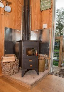 a stove in a room with a wooden wall at Old Shep's Shepherds Hut 