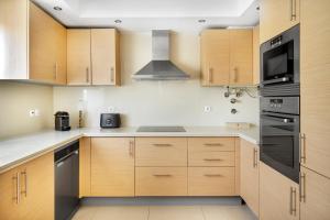 uma cozinha com armários de madeira e electrodomésticos pretos em Apartamento no Condomínio Baia Village com Piscina em Albufeira