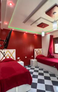 2 Betten in einem Zimmer mit roten Wänden und kariertem Boden in der Unterkunft Villa Malalien in Tétouan