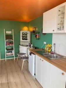 a kitchen with white cabinets and green walls at The Cat’s Cradle in Grundarfjordur