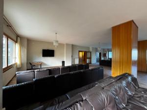 sala de estar con sofás de cuero negro y TV en Host Roccaraso en Roccaraso