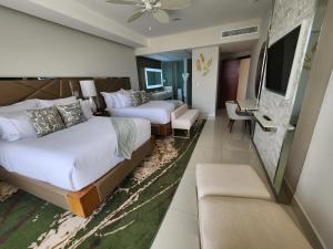 a hotel room with two beds and a television at Garza Blanca Los Cabos in Cabo San Lucas