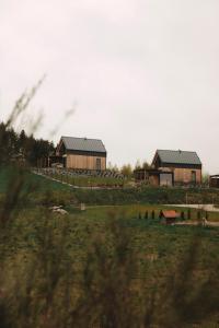 two buildings on a grassy field with trees at Garczovka - domki, jacuzzi, sauna in Garcz