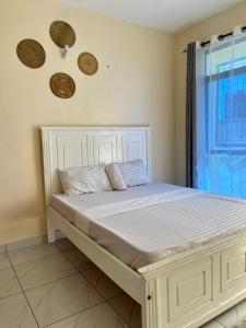 a white bed in a room with a window at Graceful Listing in Mombasa