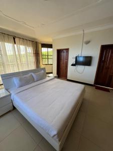 Marina Lake View Apartments,Jinja في جينجا: غرفة نوم بسرير كبير مع تلفزيون على الحائط