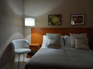 a bedroom with a bed and a chair and a lamp at BAARIA PORTO rooms in Milazzo