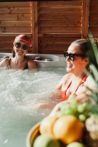 two women in a jacuzzi in a bathtub at Garczovka - domki, jacuzzi, sauna in Garcz