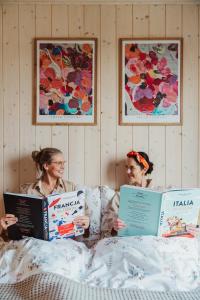 two women laying on a bed reading books at Garczovka - domki, jacuzzi, sauna in Garcz