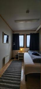 a bedroom with a bed and a table with a lamp at Gamvik brakkebo as in Gamvik