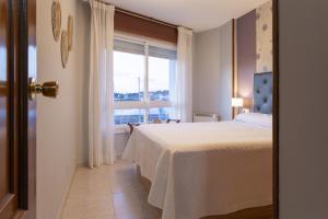 ein Schlafzimmer mit einem Bett und einem Fenster in der Unterkunft Bleumaison-a mariña portonovo in Portonovo + 18 Fotos