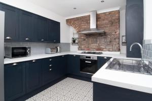 eine Küche mit blauen Schränken und einer Ziegelwand in der Unterkunft Central 4bed house, free parking in Liverpool