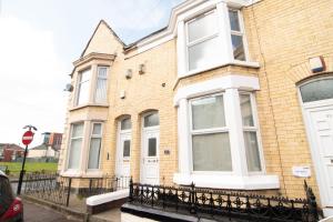 ein Backsteinhaus mit weißen Fenstern und einem Stoppschild in der Unterkunft Central 4bed house, free parking in Liverpool