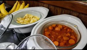una mesa con dos tazones de comida y un tazón de fruta en Hotel Araponga en Curvelo