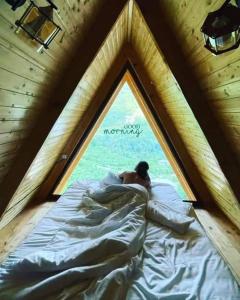 Un uomo sdraiato in un letto in una stanza con una finestra di Eco cottage sunrise merisi a Merisi