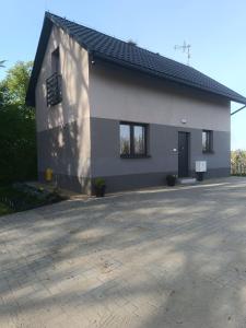 a white house with a black roof and a driveway at Domek pod lipami in Dwikozy