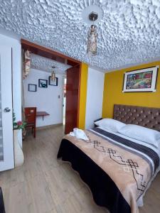 1 dormitorio con 1 cama y techo blanco y amarillo en Hostal COLUMBIA, en Moquegua