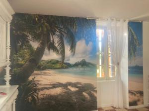 um mural de uma praia com uma palmeira numa parede em La Maison du soleil L Aulhere 3 étoiles ,Maison familiale 6-7 personnes, Spa , Massages bien-être en option em Oloron-Sainte-Marie