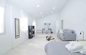 - une chambre blanche avec un lit et un canapé dans l'établissement El apartamento de San Cisneros by Just-Room, à Santander