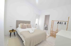 - une chambre blanche avec un lit et une table dans l'établissement El apartamento de San Cisneros by Just-Room, à Santander