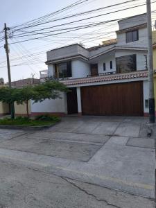 uma grande casa branca com uma garagem de madeira em Sumaq Wasi Caminos Del Inca em Lima