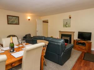a living room with a table and a leather couch at Newfield Apartment 1 in Broughton in Furness