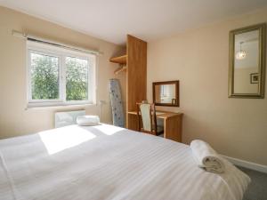 um quarto com uma grande cama branca e uma janela em Newfield Apartment 1 em Broughton in Furness