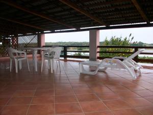 a patio with white chairs and a table on a roof at Bouganville Valledoria in Valledoria