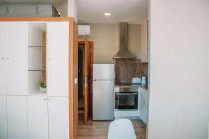 a kitchen with white cabinets and a refrigerator at Just Like Home - Vilavelha Suites in Valença +91 photos