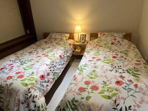 1 dormitorio con 2 camas y mesa con lámpara en Guest House" Ro" takezaki, en Amanogōchō