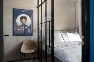 a bedroom with a bed and a chair and a poster at Daniel&Jacob's urban studios and boutique apartments in Aarhus