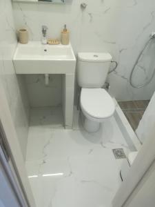 a white bathroom with a toilet and a sink at Villa Christina in Kithnos