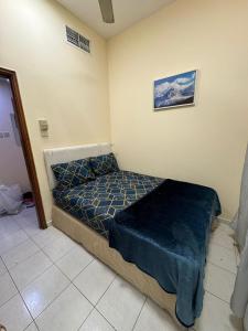 a small bedroom with a bed with a blue blanket at Decent Private family Rooms with Shared washroom next to Burjuman Metro in Dubai