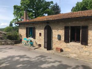 Spacious house with private garden in Chianti في Lucolena in Chianti: منزل حجري قديم مع مصاريع بنية اللون على شارع