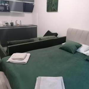 un letto verde con asciugamani sopra in una stanza di КарпатиКайзервальд. a Karpaty