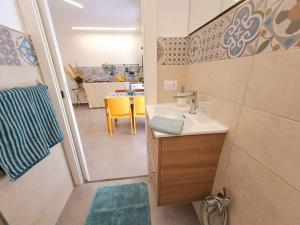 a bathroom with a sink and a table with a yellow chair at Casa Taormina in Letojanni +19 photos