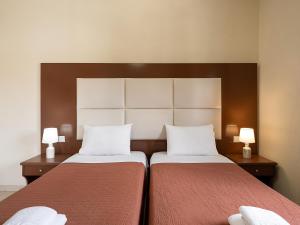 two beds in a hotel room with two lamps at Sofia Apartments in Kalamaki Chanion